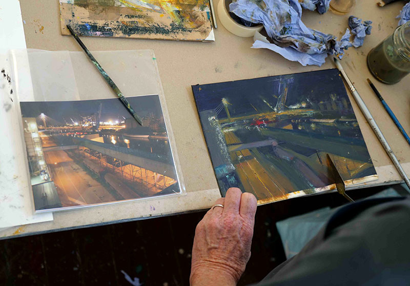 Someone painting from an image of a dimly lit road at night.